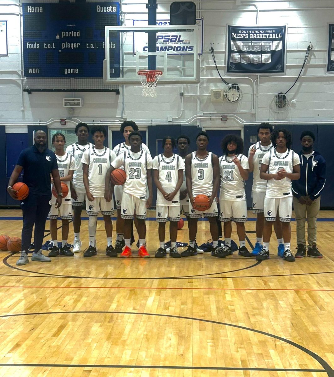 Coach Paul Campbell (pictured wearing dark blue, far left) and the boys Varsity Basketball Team. 